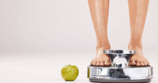Person standing on a scale with apple nearby to lose weight quickly